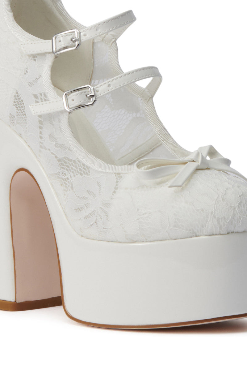 Close-up of the AZALEA WANG SPROUT WHITE PUMP, a white lace platform shoe with an almond toe, chunky high heel, two buckle straps, a decorative bow on the toe, and a soft beige sole. 6