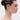 A woman with dark hair in a bun wears NOT SORRY HAIR GEMS that spell “NOT SORRY” on her head. She stands in profile against a plain, light background with a neutral expression.