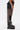 A person wearing black boots, black shorts, and the STEPHANIA TRANSPARENT TROUSER IN BLACK with pocket details stands sideways against a plain white background.