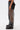 A person stands sideways wearing the STEPHANIA TRANSPARENT TROUSER IN BLACK, featuring a wide-leg mesh design over black shorts and paired with black platform boots. The plain white background highlights the geometric style of the trousers.