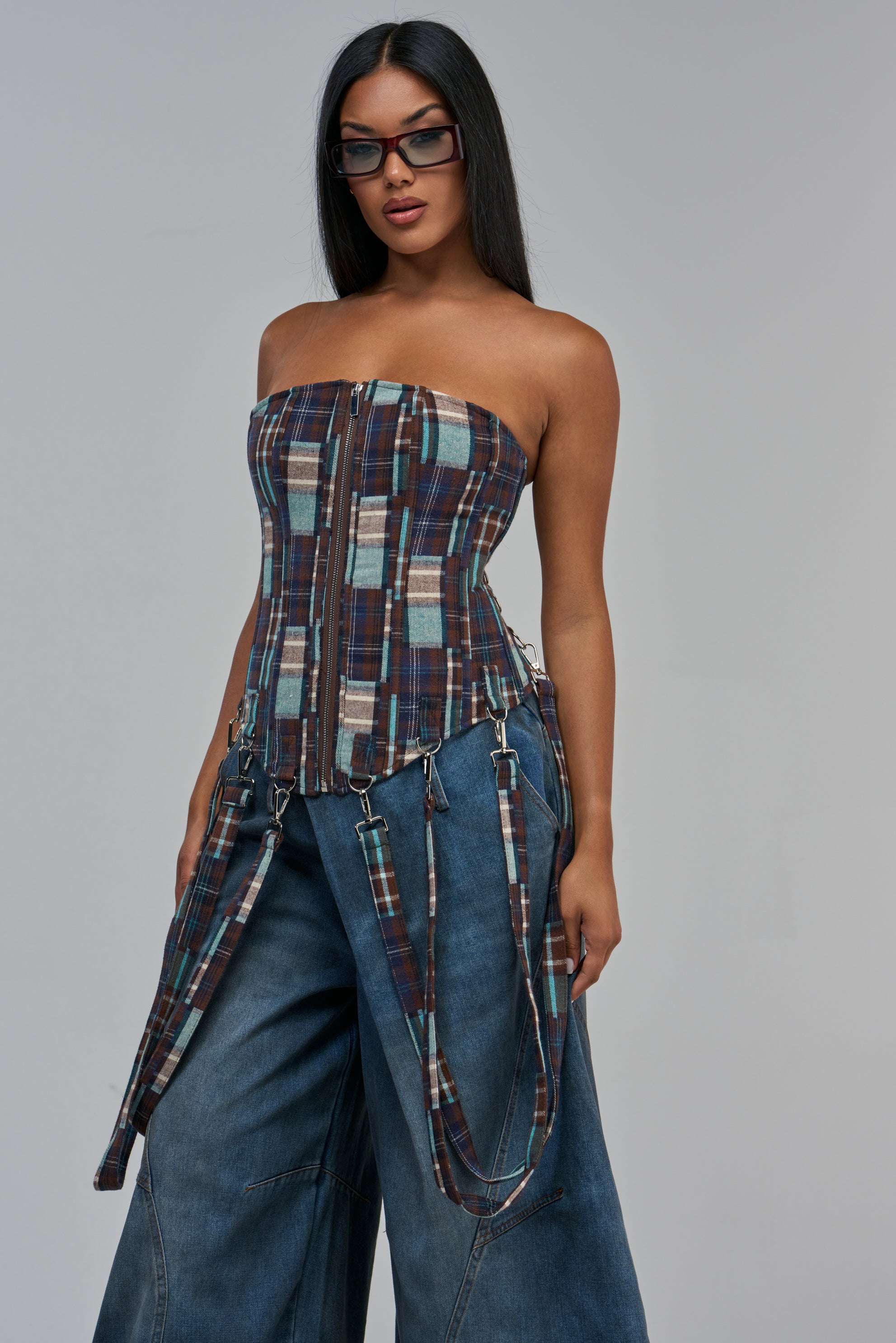 MIXED EMOTIONS PLAID CORSET, a strapless plaid corset top with a center front zipper and attached long side straps, cinched at the waist and worn with wide-leg blue jeans.
