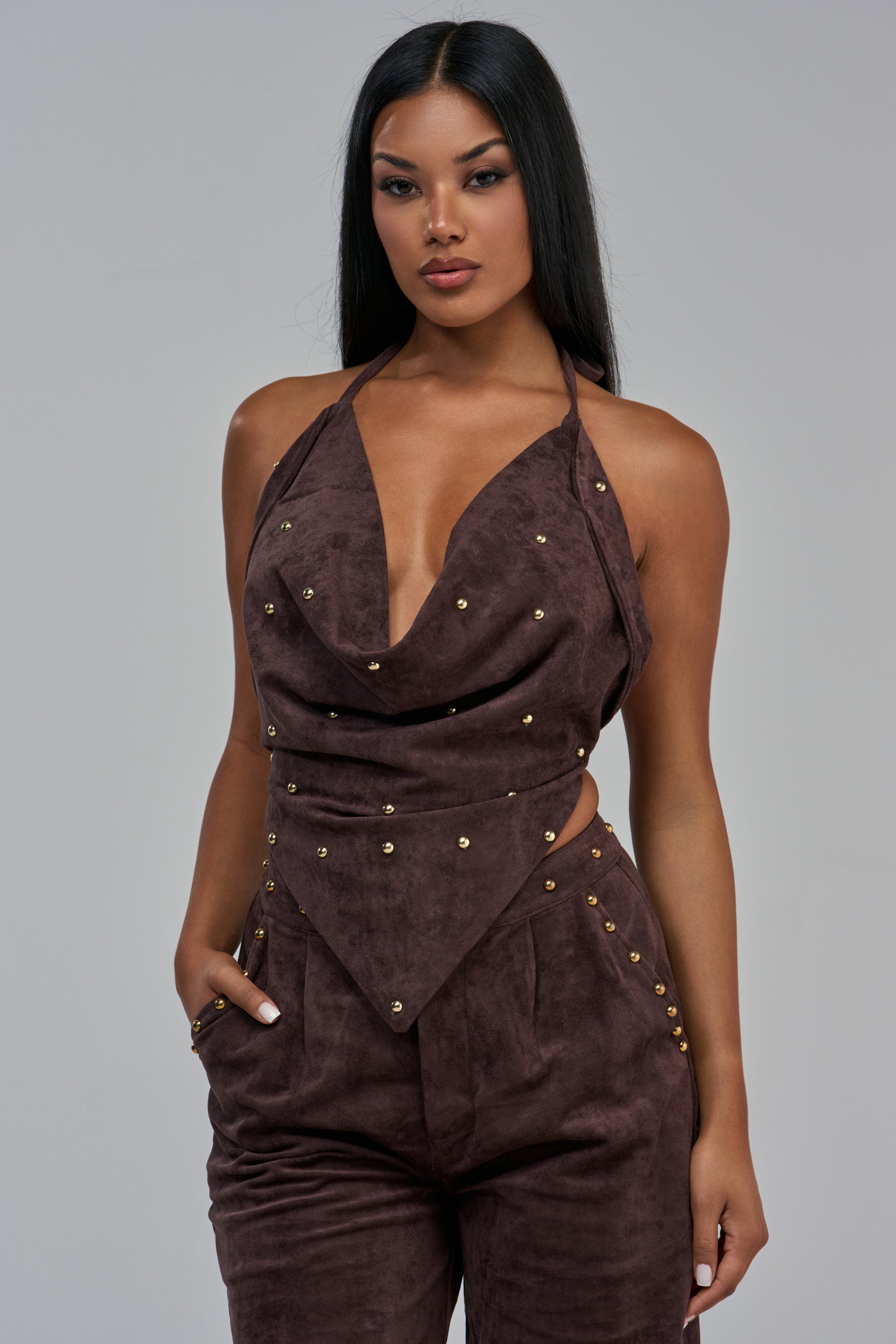 The GIA SUEDE COWL TOP is a brown faux suede halter top featuring a cowl neckline and gold stud accents.
