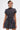 A person with short dark hair models the THAT GIRL PLAID MINI DRESS—a short-sleeved, high-neck mini dress with a smocked bodice and flared bubble skirt—while standing against a plain white background.