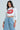 Wearing a cropped white Lips Button Down Top featuring a bold, bedazzled red lip graphic, and light blue wide-leg jeans decorated with small white dots against a plain light gray background that highlights the outfit's poplin charm.