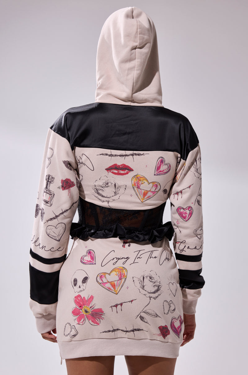 A person is seen from the back wearing the SNATCH ME UP CORSET SWEATSHIRT DRESS, an oversized hoodie dress with black accents and graphic designs like hearts, lips, flowers, and handwritten text.