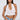 A woman with long dark hair wears the TIED TO YOU FRINGE TANK, a sleeveless white lace mesh cropped top, paired with light blue jeans, large hoop earrings, gold bracelets, and a white bag against a plain light background.
