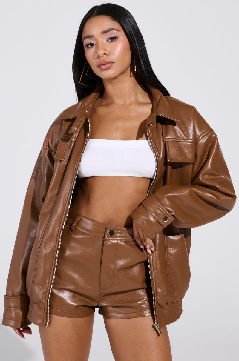 Wearing a brown BIRDIE OVERSIZED BOMBER jacket with matching shorts and a white tube top, a person with long black hair poses seriously against a plain background, exuding chic confidence.
