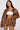 Wearing a brown BIRDIE OVERSIZED BOMBER jacket with matching shorts and a white tube top, a person with long black hair poses seriously against a plain background, exuding chic confidence.