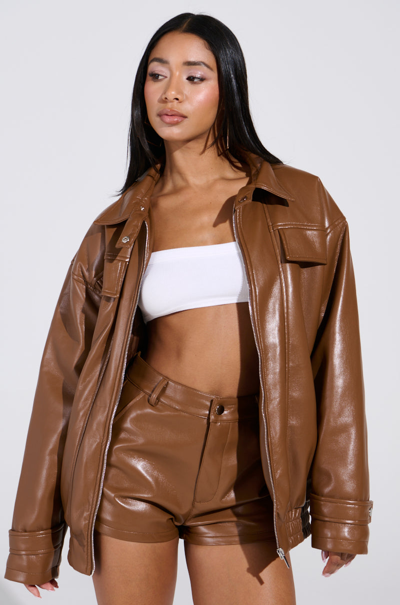 A person with long hair wears the BIRDIE OVERSIZED BOMBER and matching shorts. A white crop top is underneath, while the jacket's quilted interior adds texture. The background is plain gray.