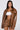 A woman with long dark hair models the BIRDIE OVERSIZED BOMBER—brown with a quilted interior—paired with matching shorts and a white crop top. She stands against a plain white background, gazing directly at the camera.