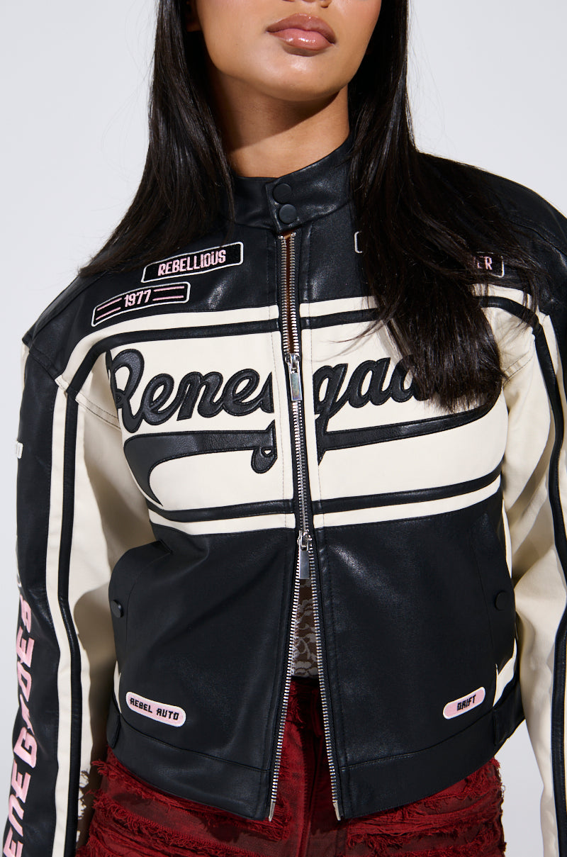 Wearing the RENEGADES EMBROIDERED MOTO, a black and white faux leather jacket with "Renegades" stitched prominently in a color block style adorned with patches and a zip-up front, the individual’s long, dark hair falls elegantly as the photo captures from shoulders to mid-torso.