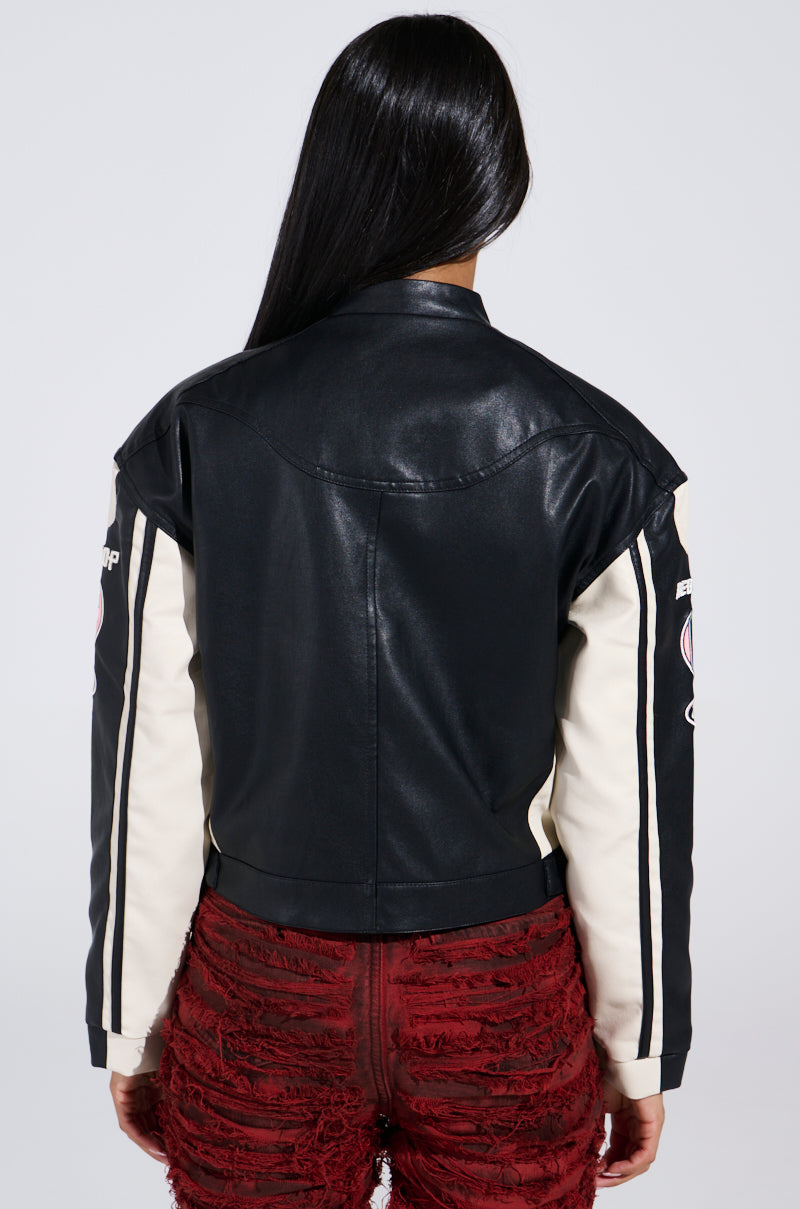 A person with long dark hair is seen wearing a RENEGADES EMBROIDERED MOTO jacket, which features beige sleeves with patches, and red textured pants with a frayed design.