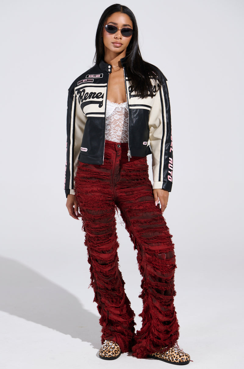 A person wearing sunglasses, a RENEGADES EMBROIDERED MOTO jacket over a lace top, red textured pants, and leopard print shoes stands confidently against a plain background.