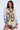 A woman in the RYAN Colorblock Rhinestone Jersey Mini Dress in pastel, featuring rhinestones, black and white striped cuffs and collar, and a bold leopard-print 