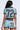 A person with long dark hair is seen from behind wearing the REBEL COLLARED TOP and matching shorts, both featuring a colorful zigzag pattern and a bold brown number 72.