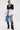Wearing the DON'T TRIP ZIPPER BLAZER over a black lace bra, with sunglasses, layered necklaces, baggy denim shorts, and black boots with silver chains, a person stands confidently against a plain background.