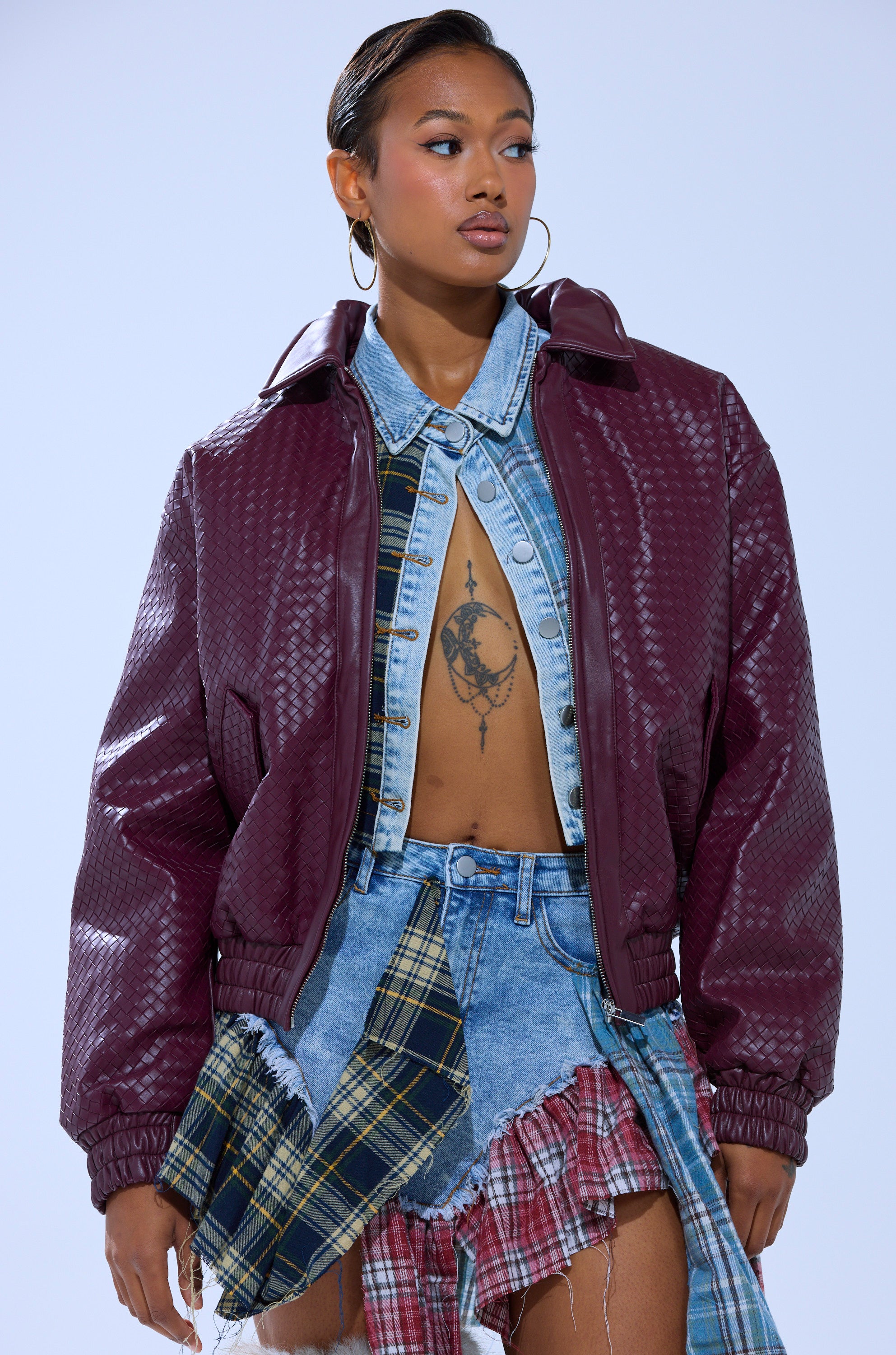 Wearing the CHERRY POP BOMBER over a denim shirt, she reveals a chest tattoo and pairs a patchwork skirt with hoop earrings and slicked-back hair for a bold, expressive style.