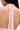 A close-up shows the upper back of a person wearing the ALL EYES ON ME MINI DRESS IN PINK, featuring delicate floral lace fabric and a neck tie with a lace bow. The skin and detailed lace design are clearly visible.