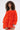 A woman with curly hair models the IN THE NAME OF FASHION RUFFLE MINI DRESS in bright orange, featuring a plush, textured finish and off-the-shoulder long sleeves, standing out against a plain light background.