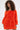A woman with curly hair wears the IN THE NAME OF FASHION RUFFLE MINI DRESS—a bright orange, off-the-shoulder mini dress with textured, ruffled fabric—standing against a plain white background.