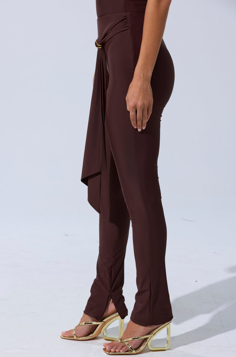 Wearing the KIMMY SEAMLESS LEGGING IN BROWN, styled with strappy gold high-heeled sandals, a person stands against a plain light background. 3
