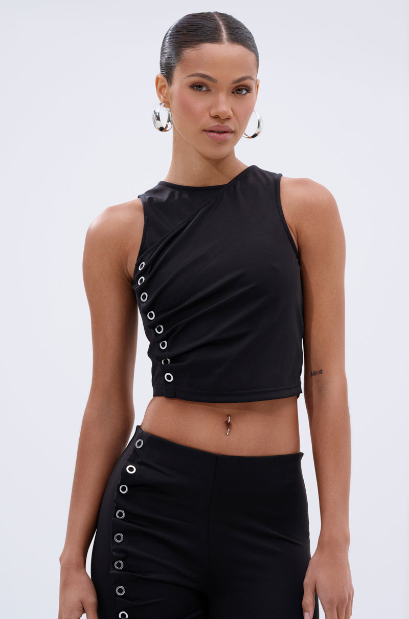 A woman with slicked-back hair and large hoop earrings wears the GROMMET DETAIL RUCHED TANK TOP, paired with matching high-waisted pants, against a plain light background. 1