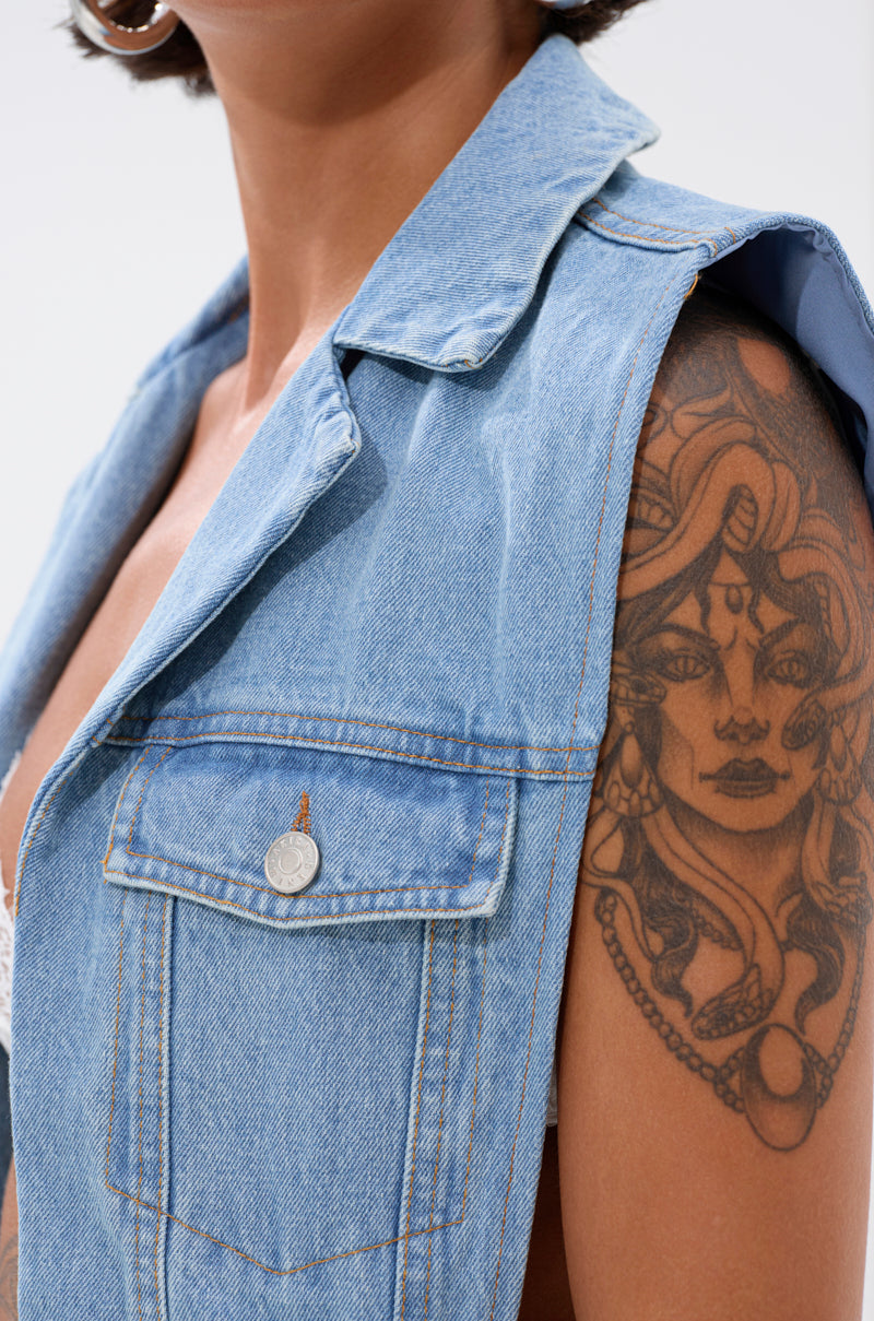 Someone wears the DOWN TO IT SPLIT DENIM VEST, showcasing a detailed tattoo of a woman's face with ornate jewelry and designs on their upper arm against a light, neutral background. 6