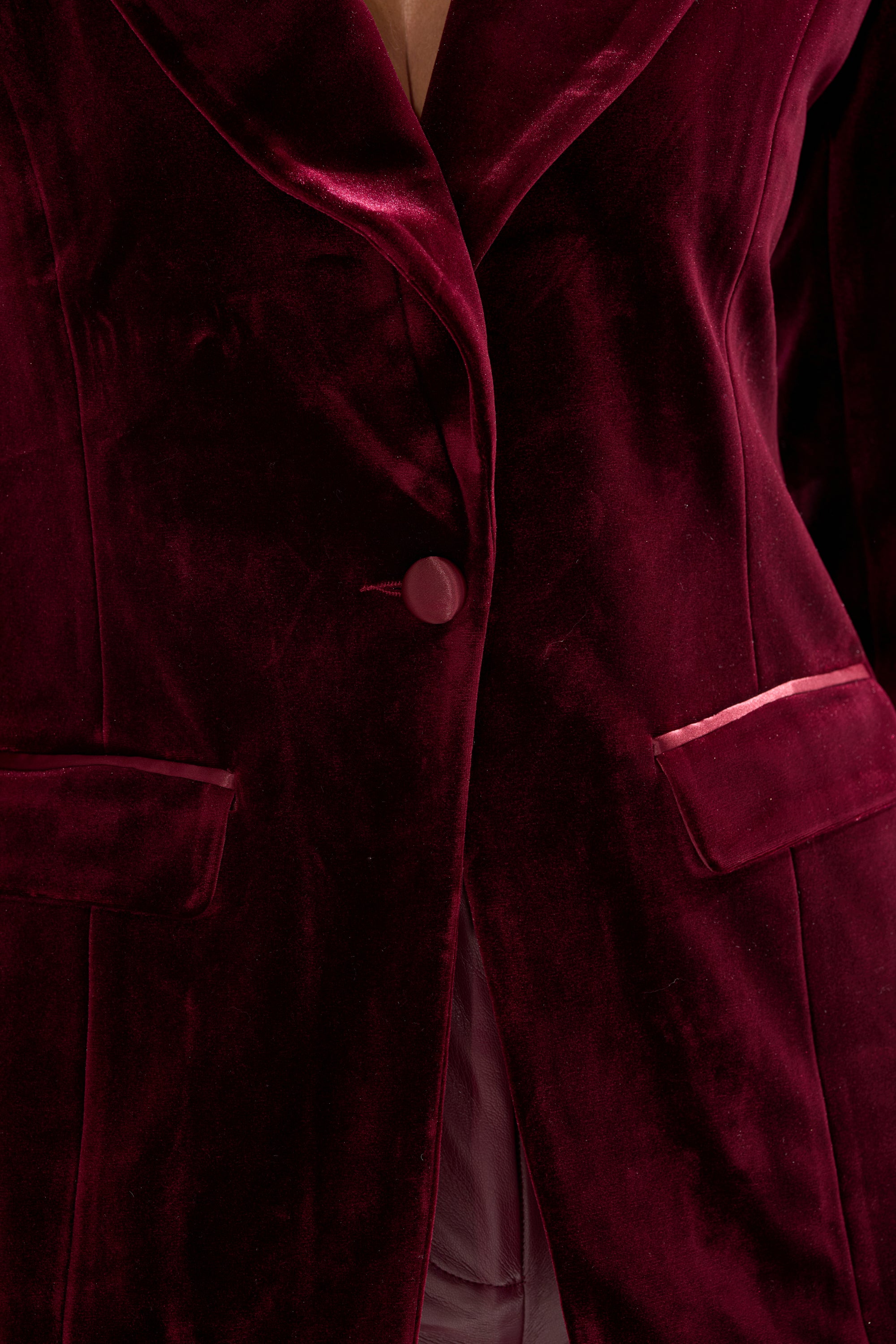 A close-up of the LUXE VELVET TUXEDO BLAZER in red, featuring one button fastened, two flap front pockets, and plush, soft fabric with a subtle sheen for a refined, luxurious look.