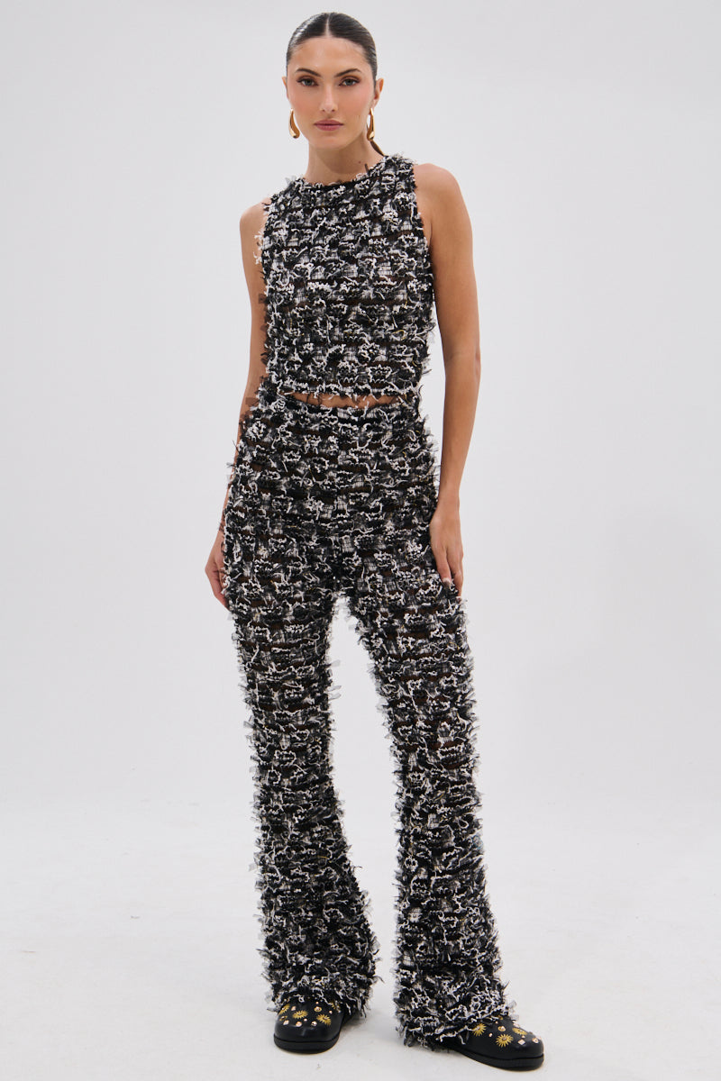 A woman stands confidently against a plain background, wearing CRAZY FOR YOU FRINGE FLARE LEGGING and a matching sleeveless, textured black and white top with black shoes—an eye-catching look ideal for music festivals. 0