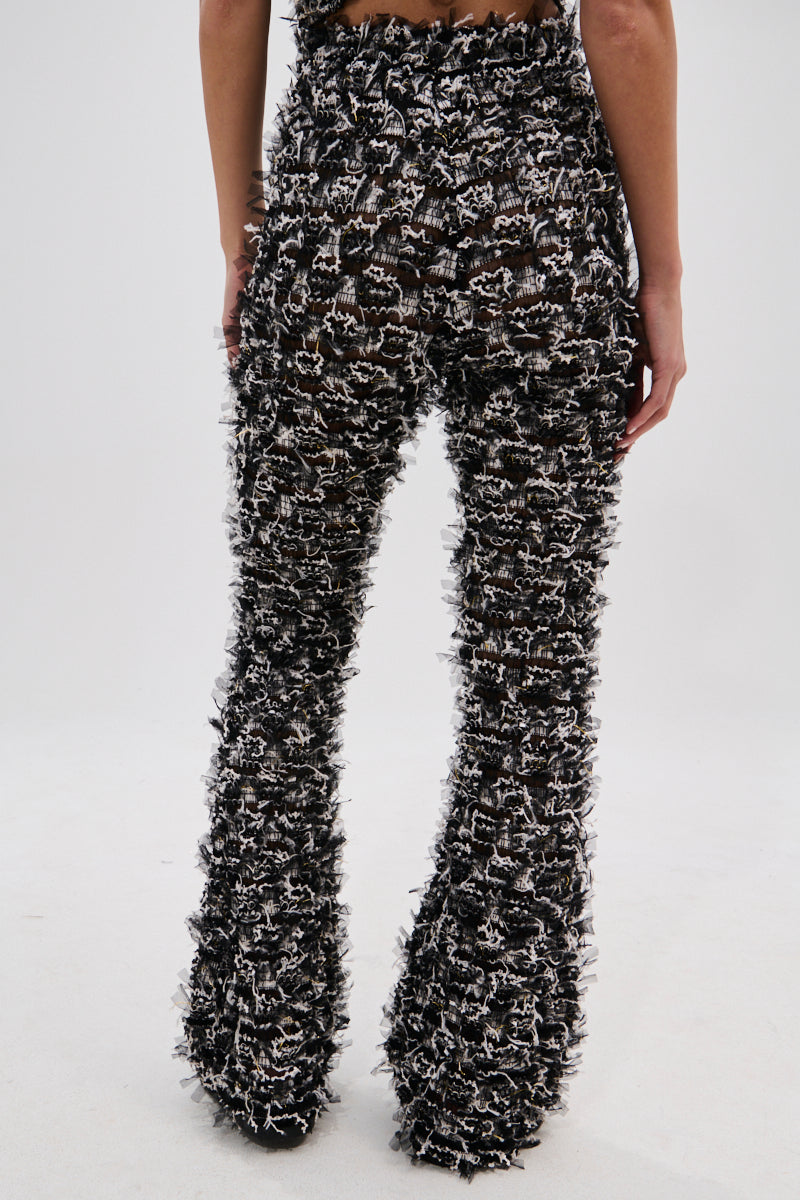 Someone wearing the CRAZY FOR YOU FRINGE FLARE LEGGING—high-rise, flare pants with a fuzzy fringed design—photographed from the back against a plain light background, ideal for music festivals. 4
