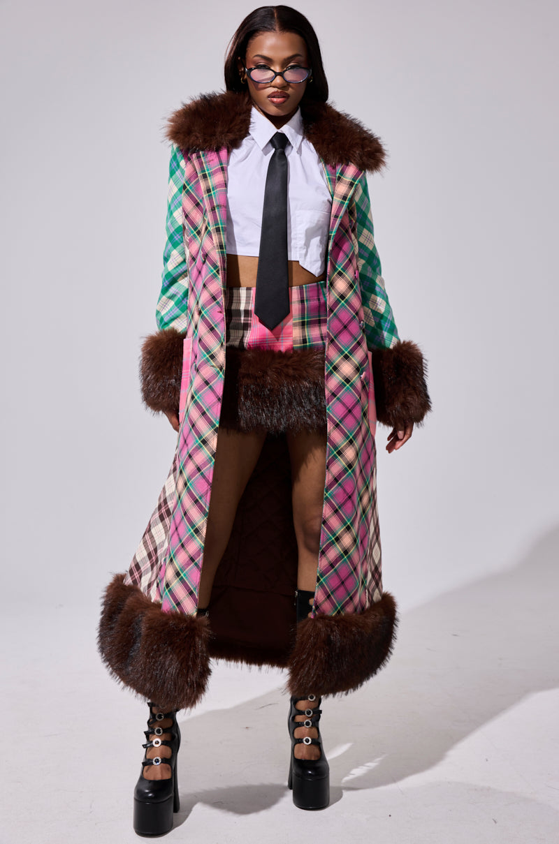 A woman exudes confidence in the SWEET THING PATCHWORK TRENCH, styled with bold pink plaid, dramatic brown faux fur trim, a short plaid skirt, white shirt, black tie, glasses, and platform boots for a standout look.