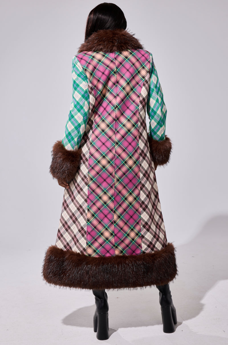 A person faces away in the SWEET THING PATCHWORK TRENCH, featuring pink plaid and cream checkered panels with brown faux fur trim at the cuffs, hem, and collar, styled with black heeled boots.
