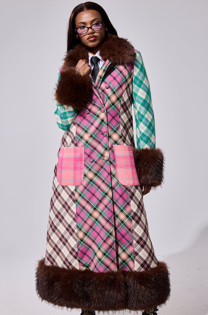 A woman wears the SWEET THING PATCHWORK TRENCH with large pink pockets and faux fur trim at the collar, cuffs, and hem, styled with glasses and a green plaid shirt paired with a black tie.