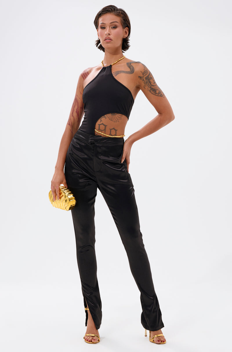 A person with short brown hair poses confidently in a black halter top and the DOWN FOR WHATEVER TROUSER, holding a gold clutch, wearing gold high heels and jewelry, with visible arm tattoos on a plain white background. 5