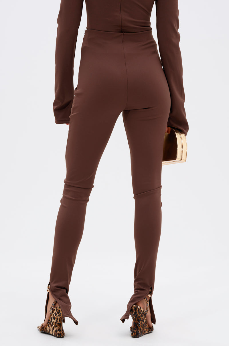 Wearing the LUX LIFE SEAMLESS LEGGING IN BROWN and a matching long-sleeve top, a person stands facing away with a gold clutch and leopard print high heels featuring cut-out ankle details. 3