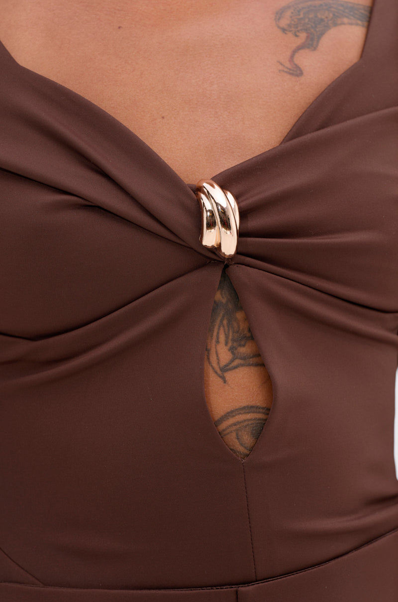 Close-up of a person wearing the LUXE LIFE SEAMLESS BODYSUIT IN BROWN, featuring a plunge neckline, twisted front design, gold metallic clasp, and small keyhole cutout revealing part of their chest tattoo.