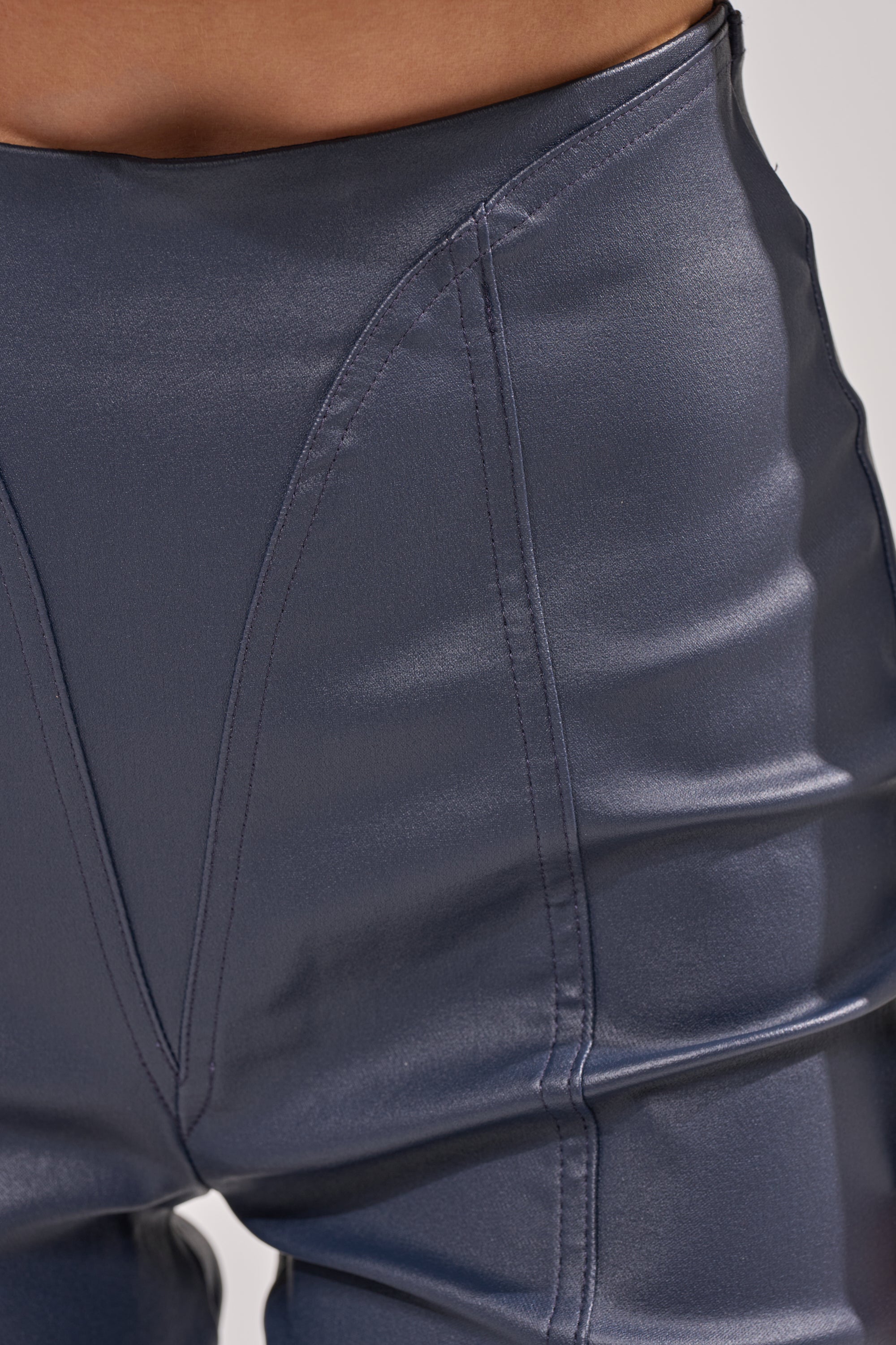 Close-up of a person wearing the BIG CITY LIVIN FAUX LEATHER LEGGING IN NAVY, featuring a shiny finish, high-waisted fit, visible stitching, and seam details. 5