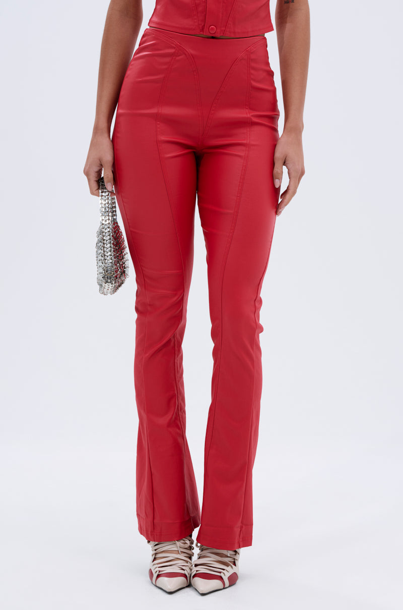 A woman wears the BIG CITY LIVIN FAUX LEATHER LEGGING IN RED, pairing it with a small silver beaded handbag and white and red pointed-toe shoes. Only her lower torso and legs appear against a plain backdrop.