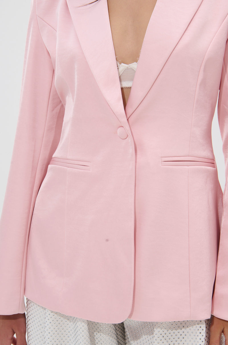 A person wears the DON'T MAKE ME BLUSH SATIN BLAZER in light pink, styled with a visible white lace bralette and patterned light-colored pants. The photo is cropped from shoulders to mid-thigh. 6