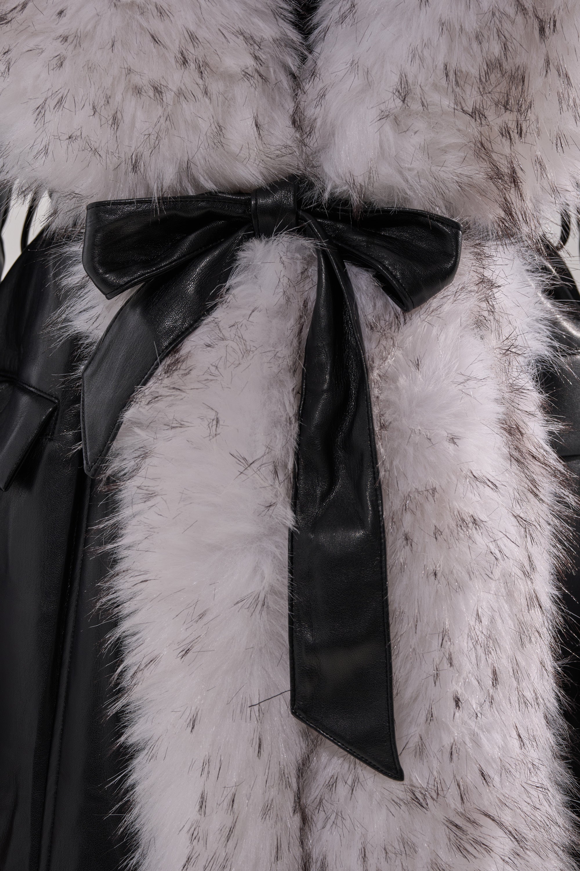 Close-up of the FIONA BUTTER LUXE FUR TRIM TRENCH, featuring fluffy light-colored faux fur trim and a black leather belt tied in a bow for striking contrast and a luxurious look.