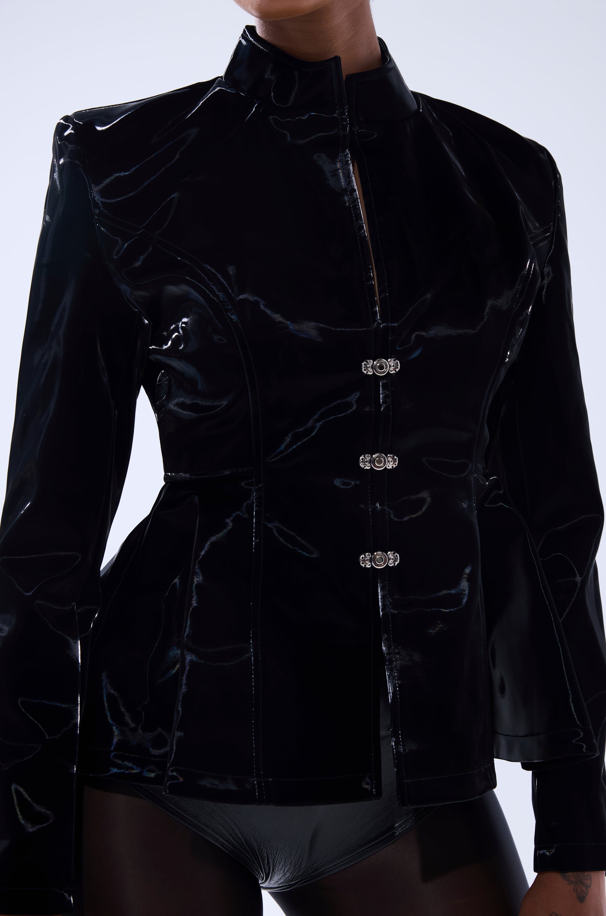 A person models the SLIMM LIQUID VELVET BLAZER—shiny black with a high collar and silver clasps—paired with matching black bottoms. The image is cropped above the nose and at mid-thigh. 5