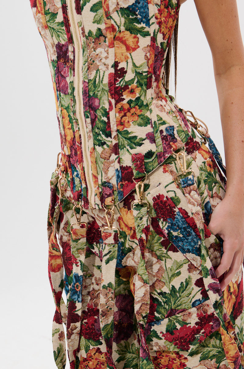 A close-up of a person wearing the FLORAL FOR DAYS BROCADE CORSET, featuring colorful floral patterns, gold zipper, and metal clasp details, set against a plain white background with only the torso and part of one arm visible.