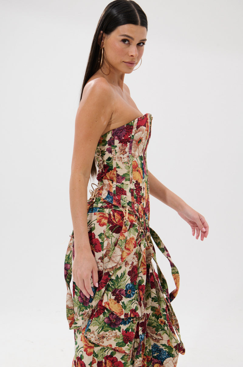 Woman with long straight dark hair models the FLORAL FOR DAYS BROCADE CORSET, a strapless dress with a fitted bodice and flowing skirt, standing against a plain white background and looking over her shoulder.