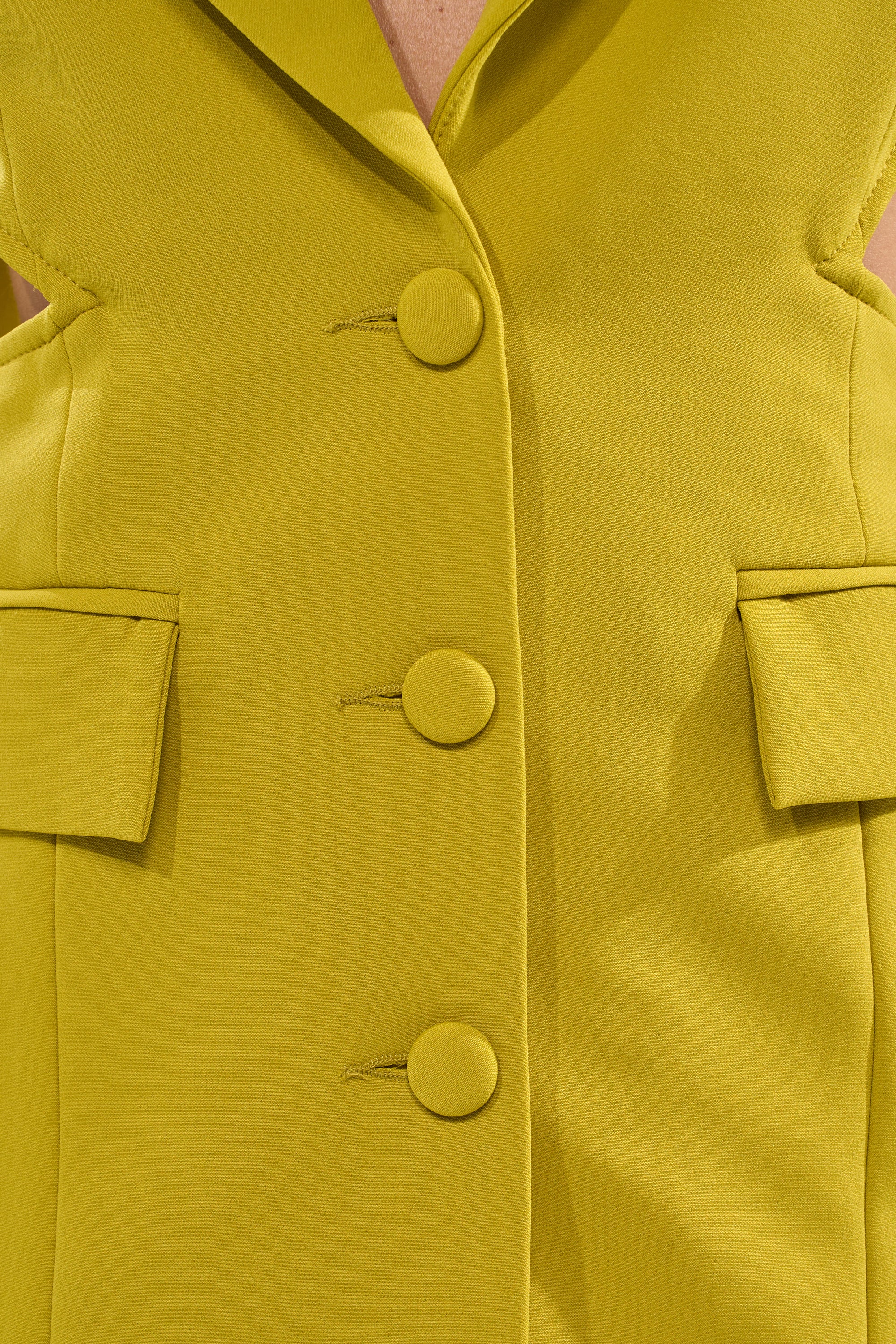 Close-up of the PARTY IN THE BACK CUTOUT BLAZER IN CHARTREUSE, featuring three fabric-covered buttons, two flap pockets, visible stitching, and a structured, tailored cut—a bold pick for modern power dressing. 8