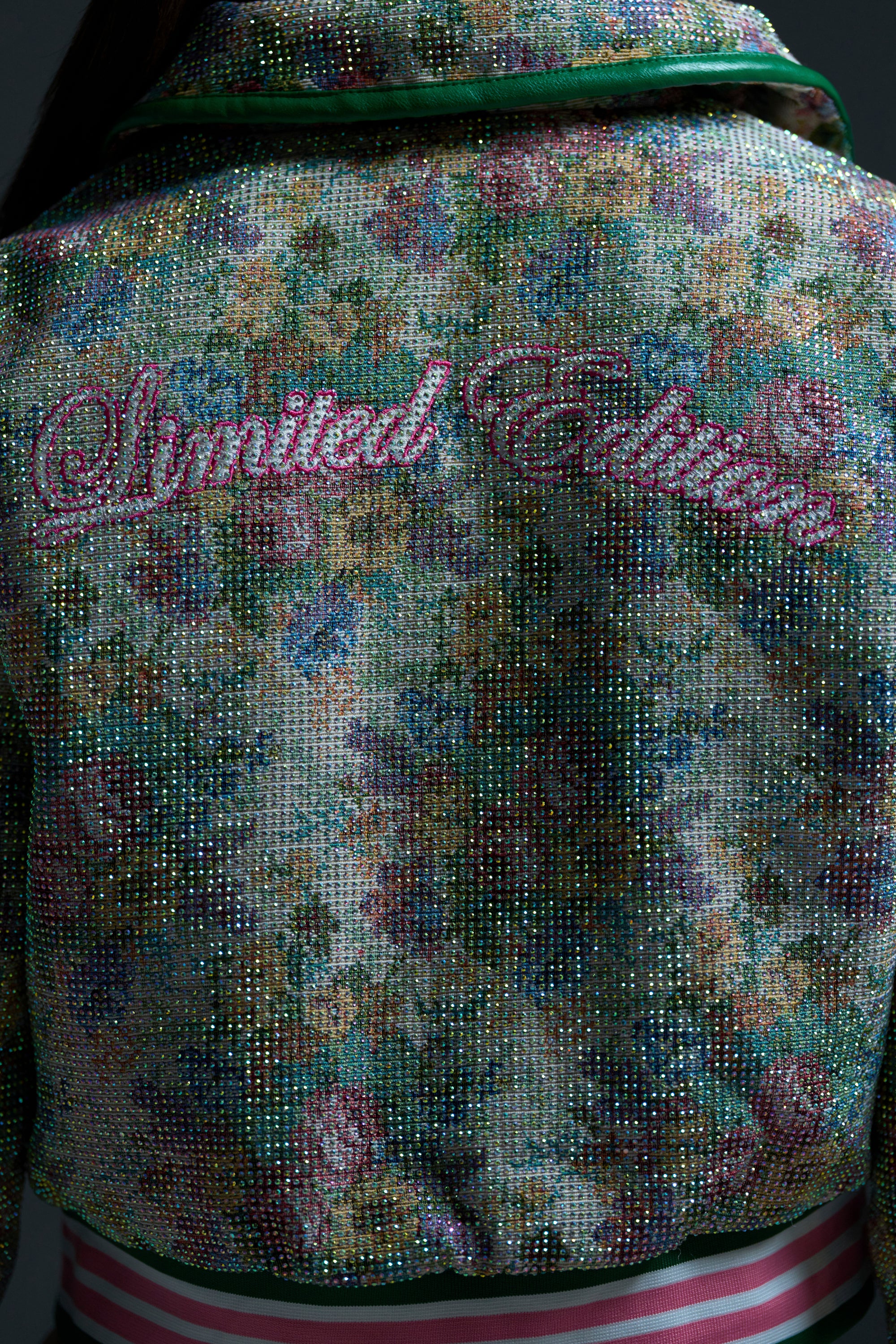 A close-up of the back of the TAPPED OUT RHINESTONE BOMBER shows a vibrant rhinestone bomber jacket with a bold floral pattern and "Limited Edition" in pink script across the shoulders.