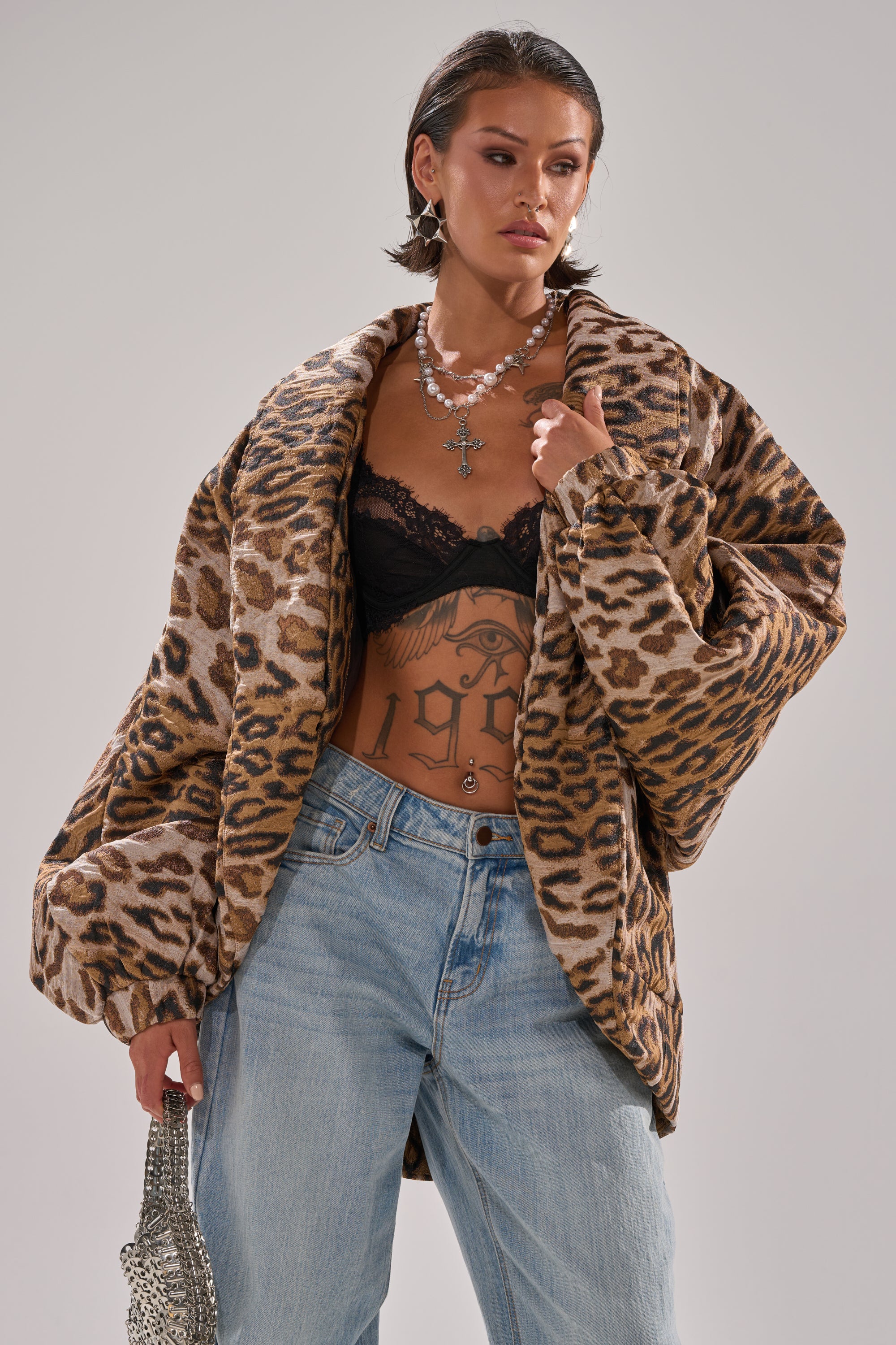 A woman wears the LOLA COCOON COAT IN JACQUARD, featuring an oversized draped collar and bold leopard print.