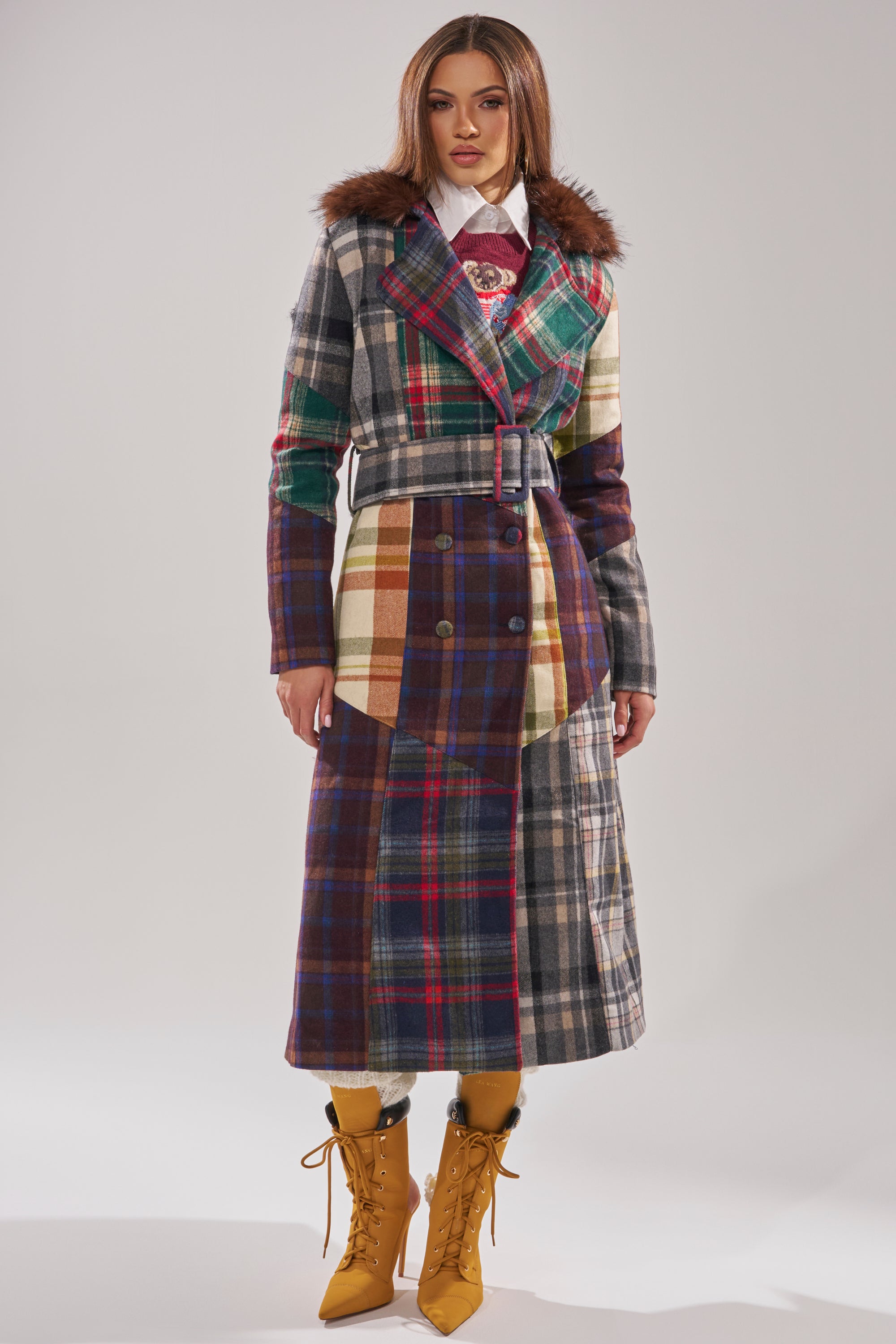A woman strides confidently in the RILEY PATCHWORK TRENCH, its plaid pattern and faux fur collar adding a touch of elegance to her look. 4