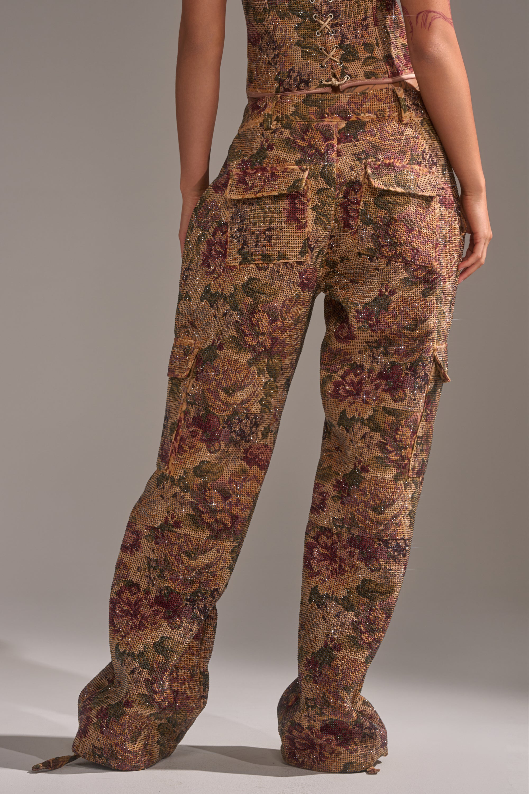 A person stands facing away, wearing the GLAM SQUAD RHINESTONE BROCADE TROUSER with a wide-leg silhouette and vintage-inspired floral print, paired with a matching corset top. 5