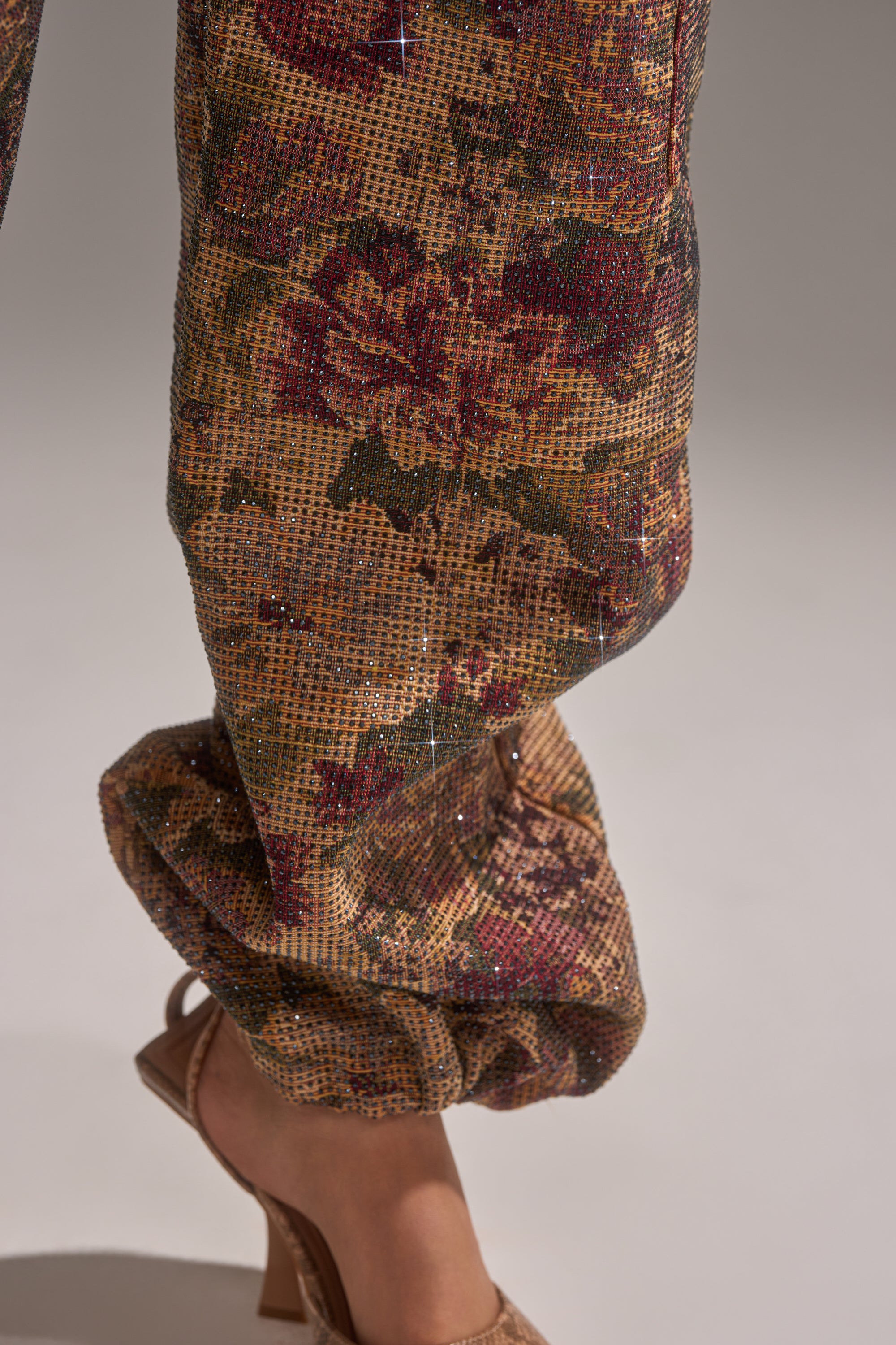 A close-up of a person’s lower leg and foot wearing the GLAM SQUAD RHINESTONE BROCADE TROUSER and an open-toe heeled sandal against a plain background. 8