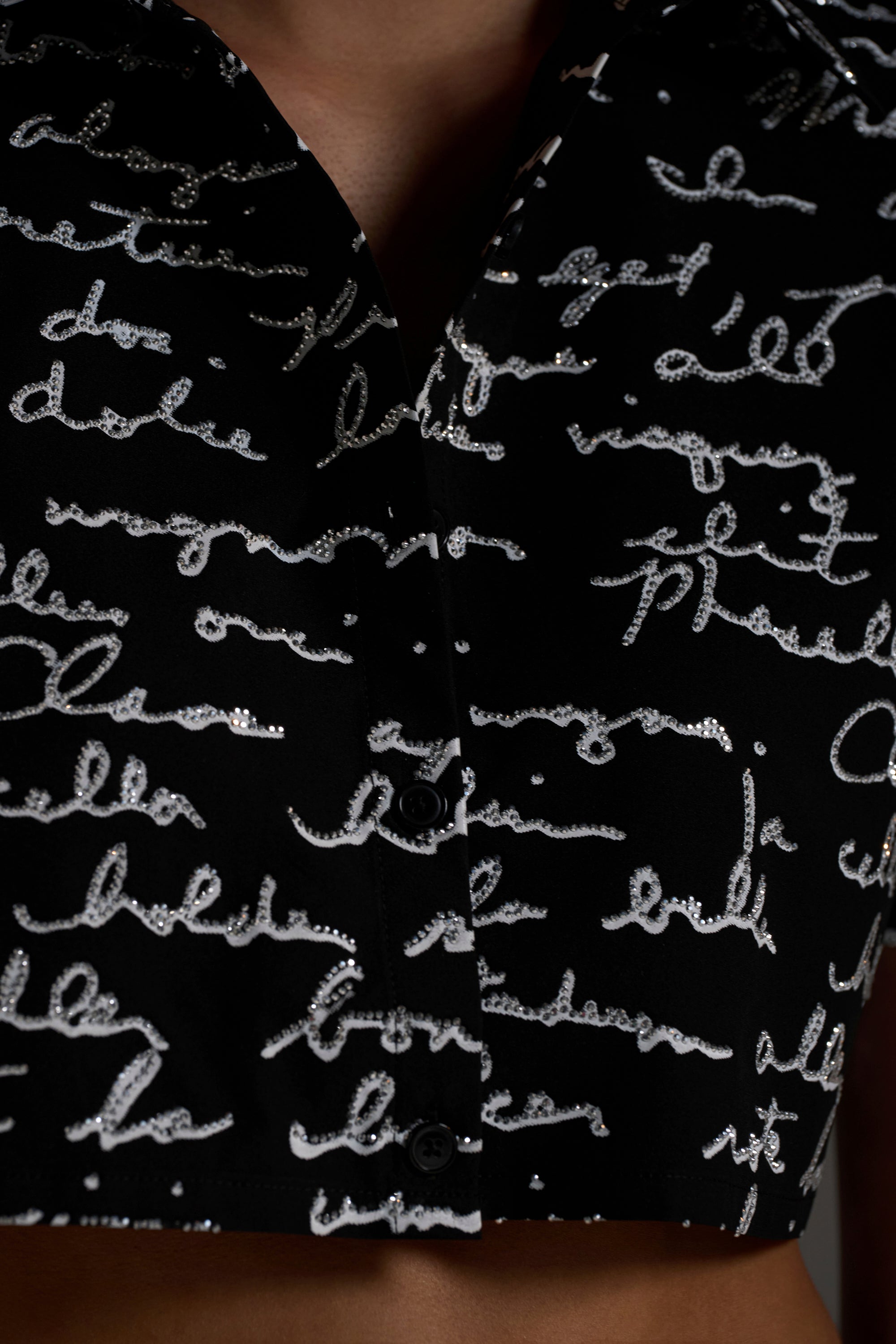 Close-up of the CHANGES BUTTON DOWN: a black button-up shirt with white, cursive, handwritten-style patterns. The shirt is partially unbuttoned, revealing a bit of skin near the collar.